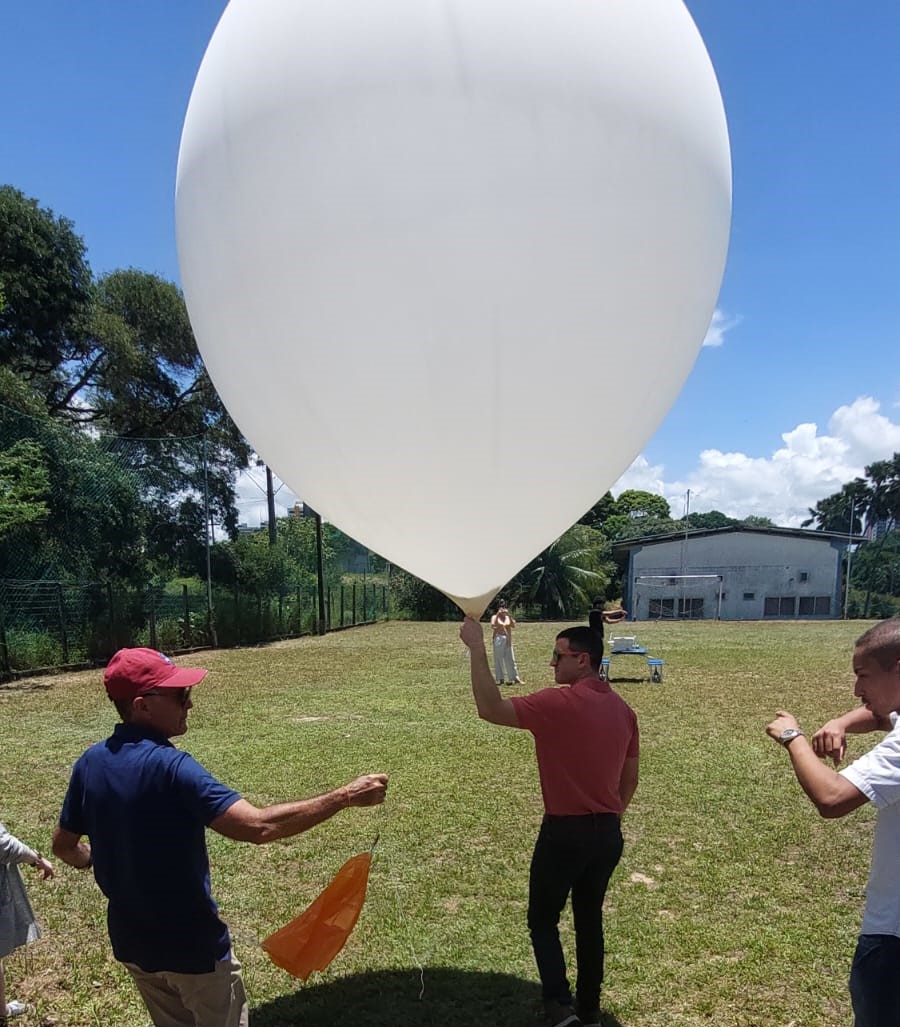 Foto do Dr Ryan e Tércio Penha levando o balão para o ponto de lançamento